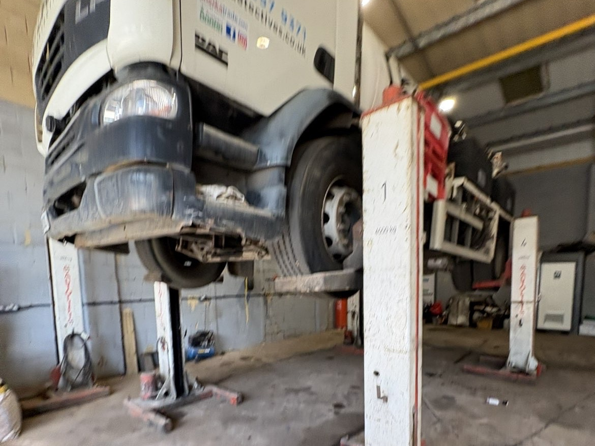 DAF lorry raised on workshop pillar lifts for underside work