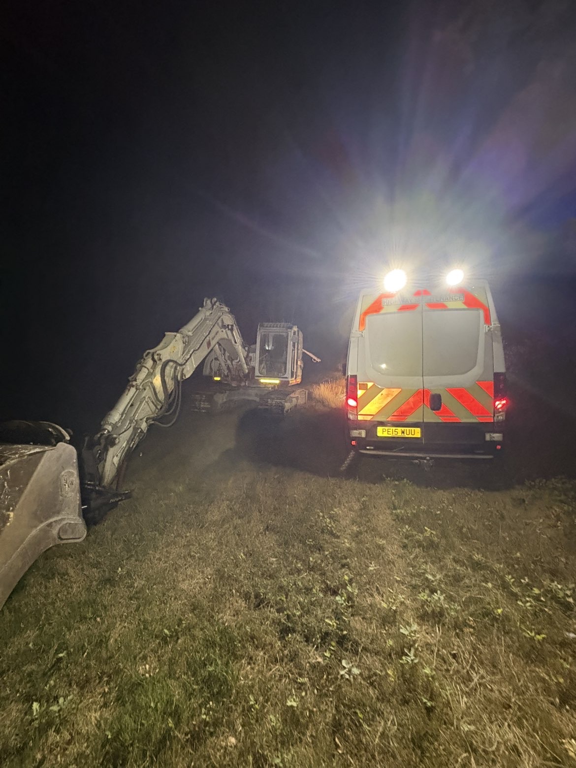 Night call-out repairing a tracked excavator lit by the service van's work lights
